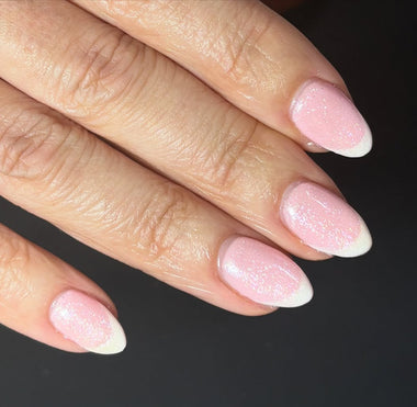Close-up of a hand with pink glittery nails on a dark background