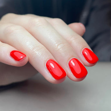 Hand with red nail polish on a blurred background
