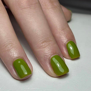 Close-up of hands with green nail polish on a light background