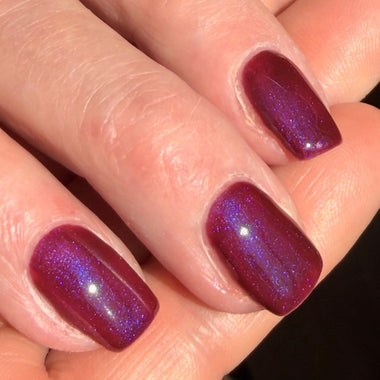 Close-up of a hand with purple nail polish on a blurred background