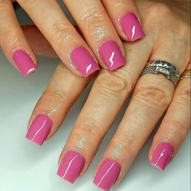 Close-up of hands with pink nails and a silver ring on a white background