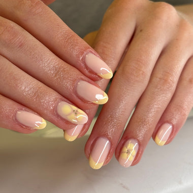 Close-up of hands with pink and yellow nail polish on a neutral background