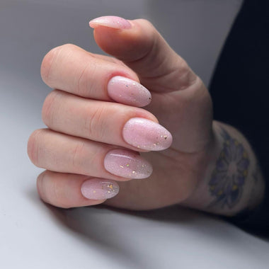 Hand with pink glittery nails on a neutral background