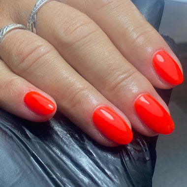 Hand with bright red nail polish on a dark background