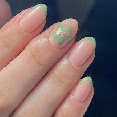 Close-up of a hand with green nail polish on a dark background
