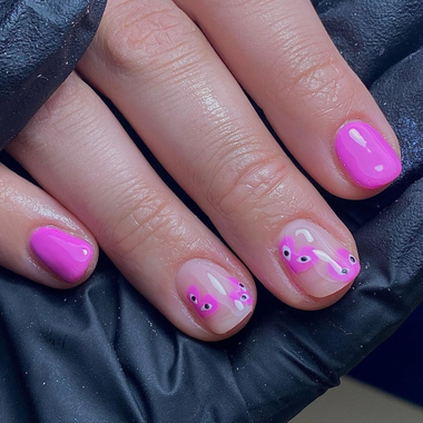 Close-up of a hand with pink nail polish and butterfly design on a dark background