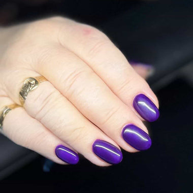 Hand with purple nail polish holding a steering wheel inside a vehicle.