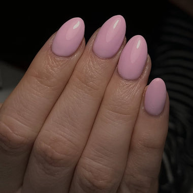 Close-up of a hand with pink nail polish on a blurred background