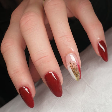 Close-up of a hand with red nail polish on a light background