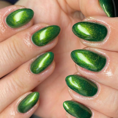 Close-up of hands with green glittery nail polish on a neutral background
