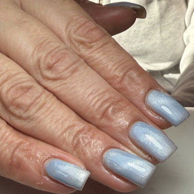Close-up of hands with light blue nail polish on a neutral background