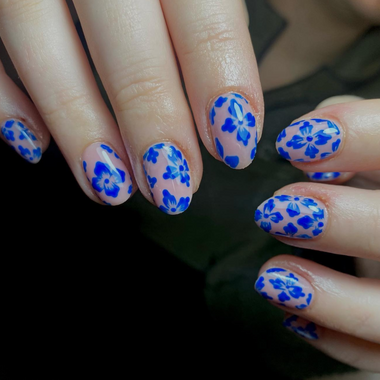 Nails with blue floral pattern on a dark background