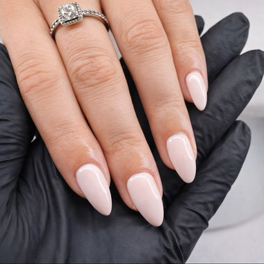 Hand with pink nail polish wearing a silver ring, against a neutral background
