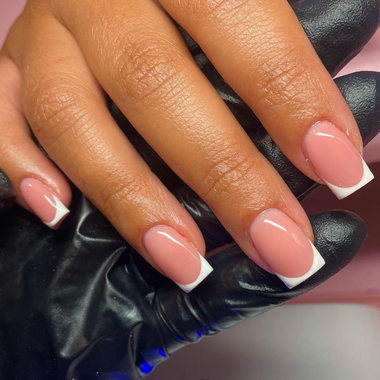 Close-up of a hand with pink nail polish on a black surface