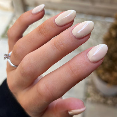 Hand with beige nail polish holding a pineapple