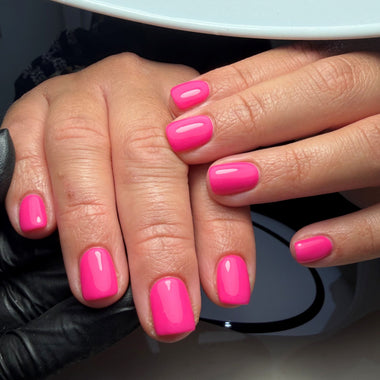 Close-up of hands with bright pink nail polish on a neutral background