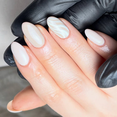 Close-up of hands with almond-shaped nails and a neutral color scheme, wearing black gloves.