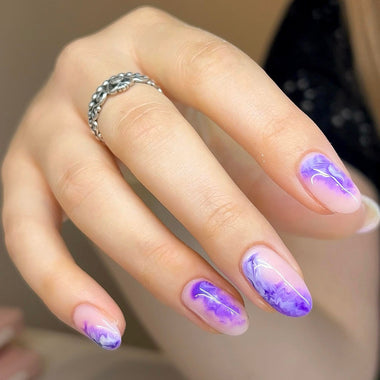 Hand with purple and pink gradient nail polish wearing a silver ring.