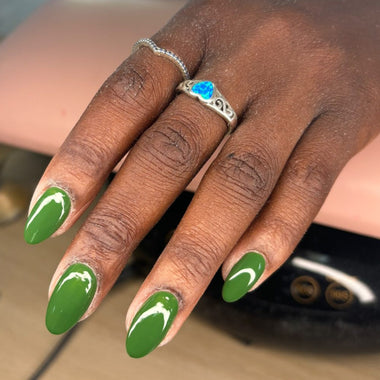 Hand with green nail polish and a ring on a blurred background