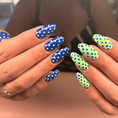 Close-up of hands with blue and green polka dot nail designs.