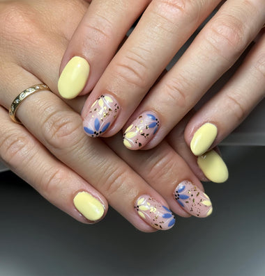 Close-up of hands with yellow and multicolored nail polish on a dark background