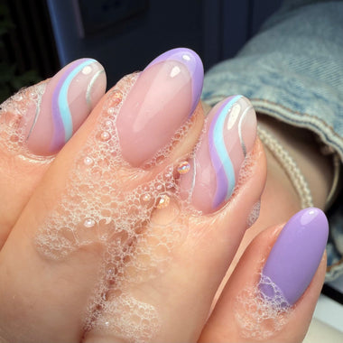 Hand with pastel nail design in a bubble bath