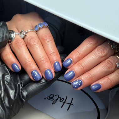 Close-up of hands with purple nail polish holding a black handbag.