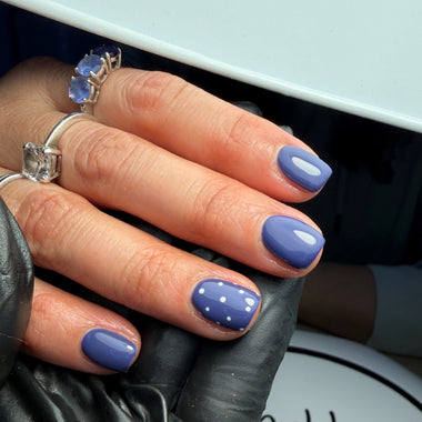 Hand with blue nail polish wearing rings, blurred background