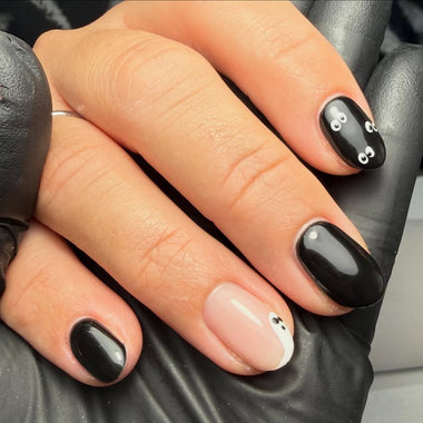 Hand with black nail polish and decorative elements on a dark background