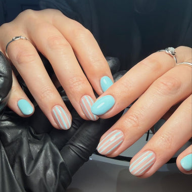Close-up of hands with light blue nail polish and white stripes, wearing black gloves.