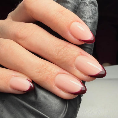 Close-up of a hand with almond-shaped nails featuring a gradient design.